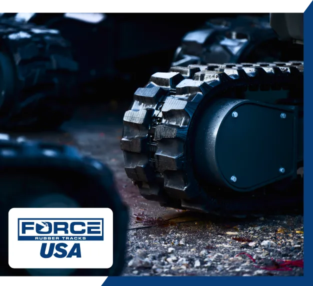 Close-up of heavy machinery rubber tracks on a stony surface, with the brand "FORCE RUBBER TRACKS USA" shown in the lower left.